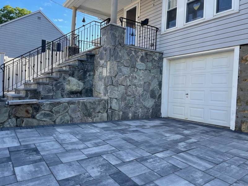 Fieldstone wall and steps beside a garage with paver drive