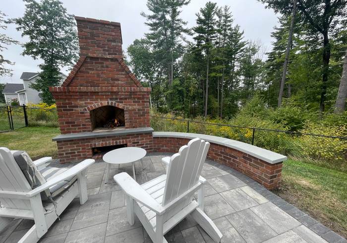 Brick outdoor fireplace with a curved seat wall and patio