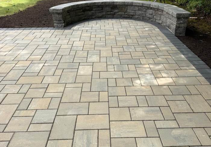 Large paver patio with a curved stone seat wall